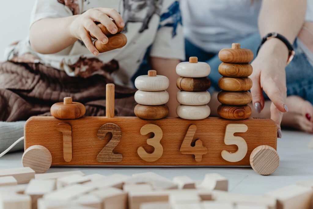 pexels-photo-7269673-7269673 A child and adult playing with wooden number toys, enhancing learning and coordination skills.